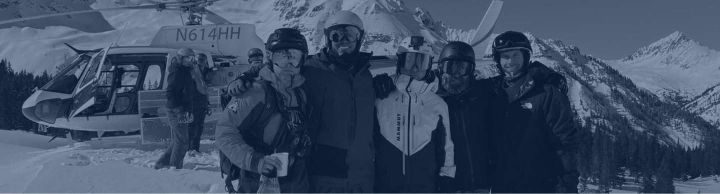 Brad and group on a mountain with a helicopter in the background